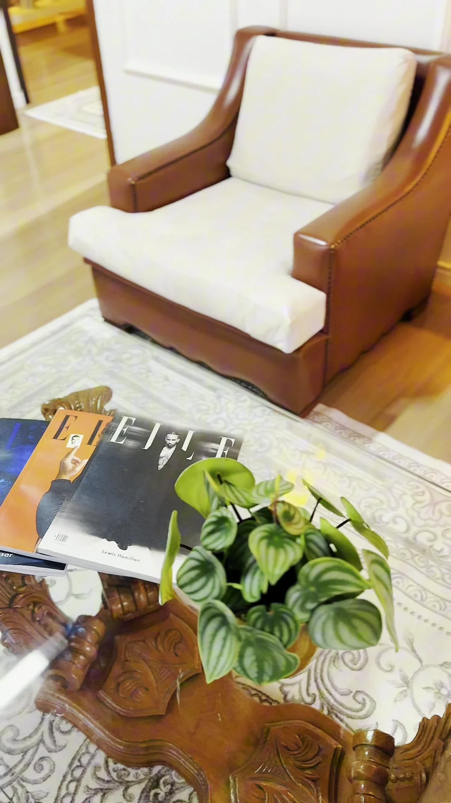 Poltrona de couro e mesa de centro com revistas na área de espera.
